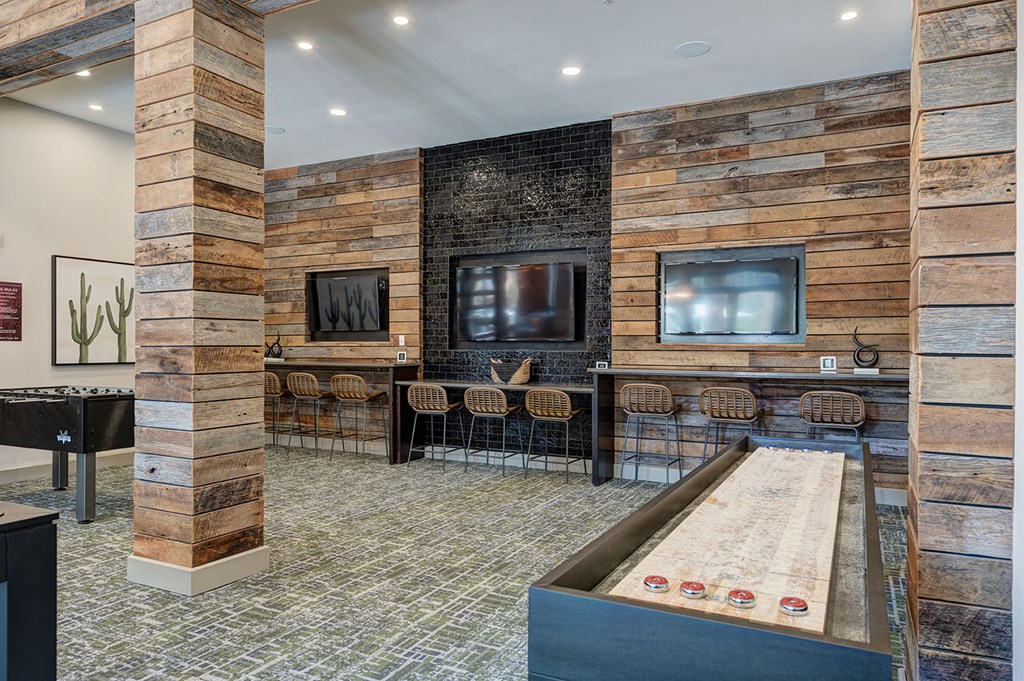A room with a shuffleboard table and a bar.