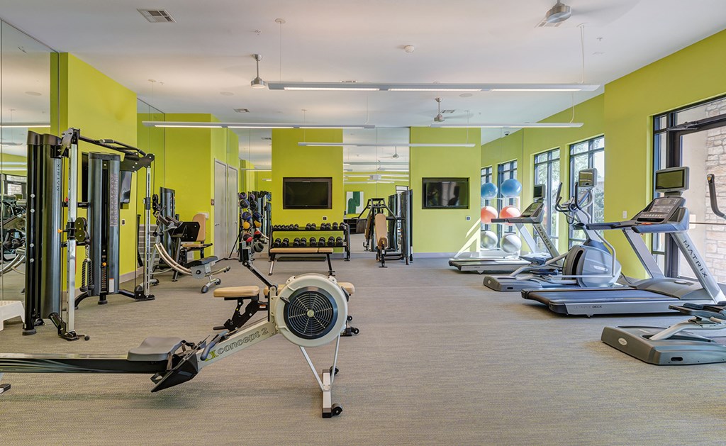 A gym with a variety of equipment including treadmills, weights, and exercise machines.