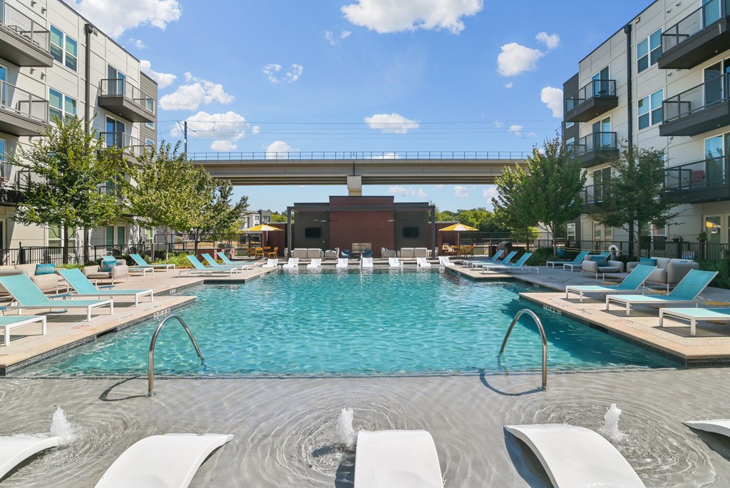 a swimming pool with lounge chairs and a bridge over it
