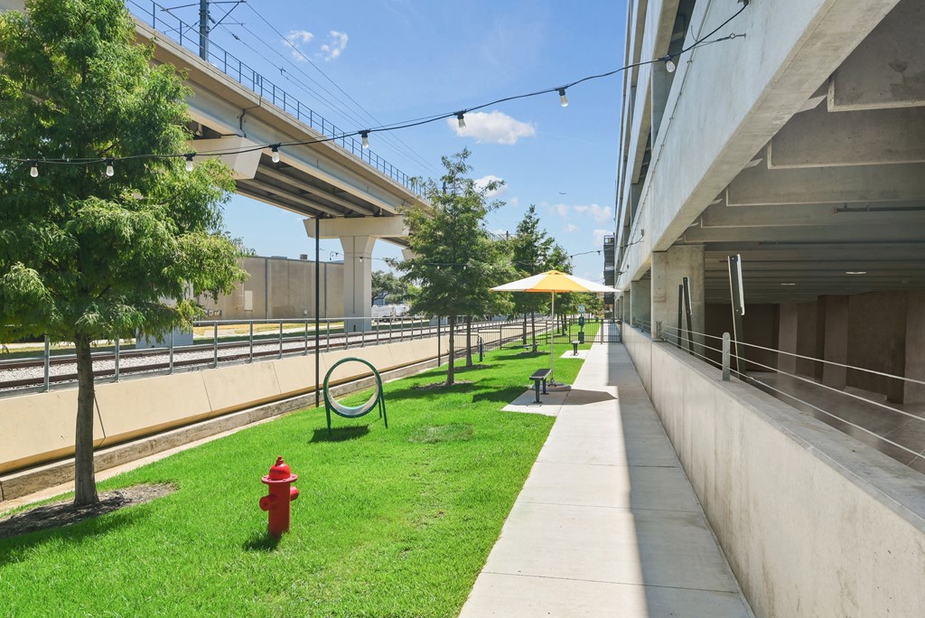 a grassy area between two buildings with a red fire hydrant