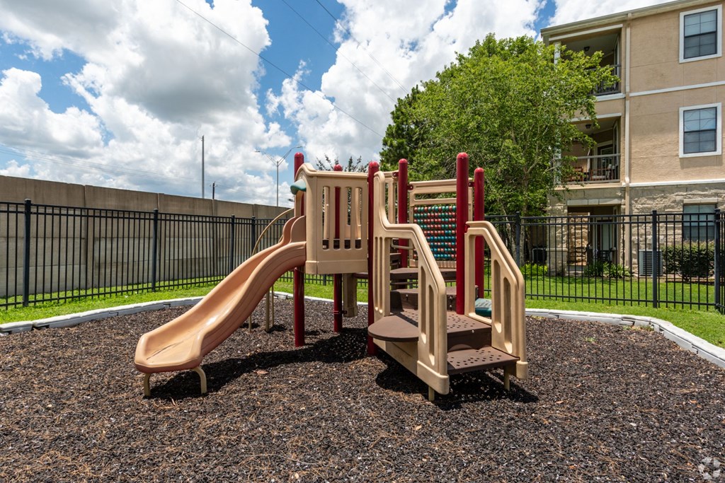 A playground with a slide, stairs, and a climbing wall.