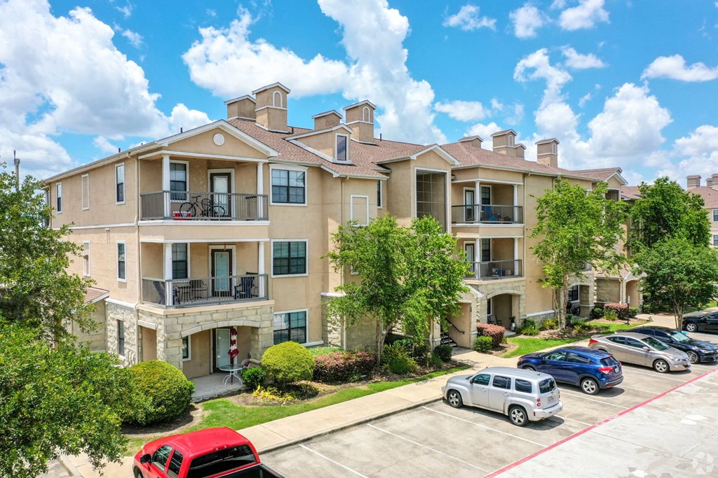 A row of townhouses with cars parked in front.