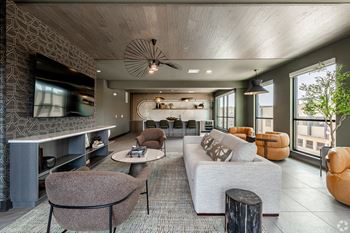 A modern living room with a grey sofa, a brown armchair, and a wooden coffee table.