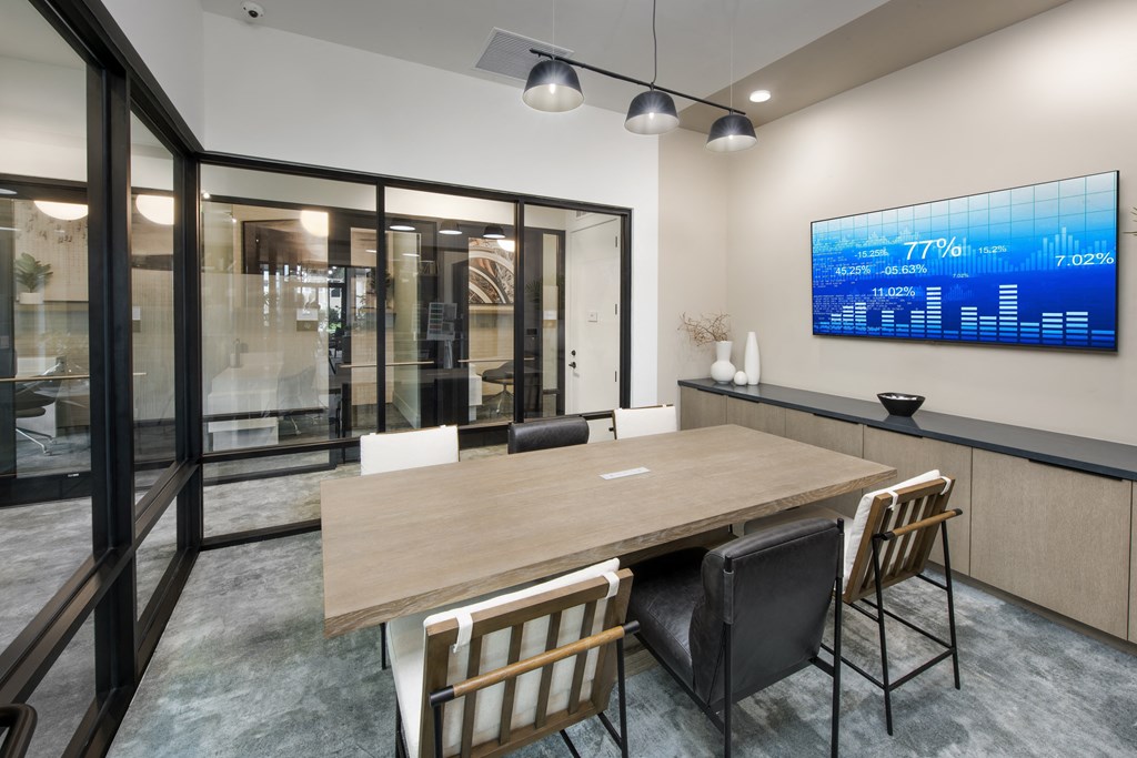 a conference room with a wooden table and chairs and a monitor on the wall
