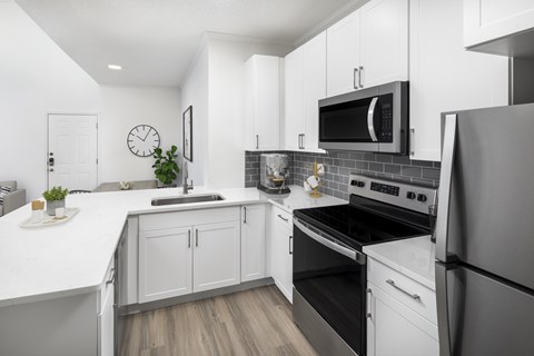 A modern kitchen with white cabinets and stainless steel appliances.