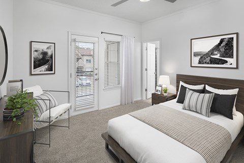 A bedroom with a large bed and a chair with a potted plant on a table.