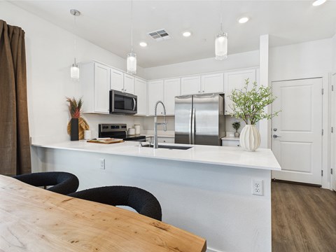 A kitchen with a wooden table and black chairs.