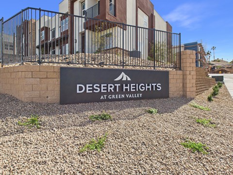 A sign that says "Desert Heights at Green Valley" in front of a building.