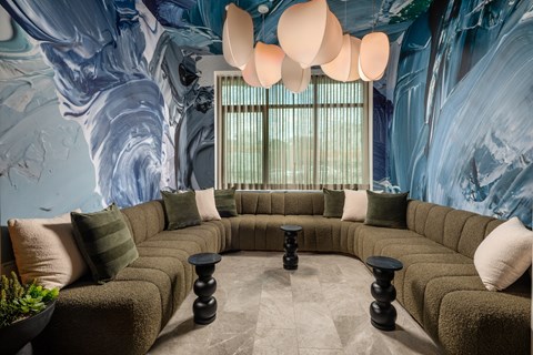 A living room with a large couch and a wall mural.