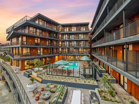 A modern apartment complex with a pool and outdoor seating area.