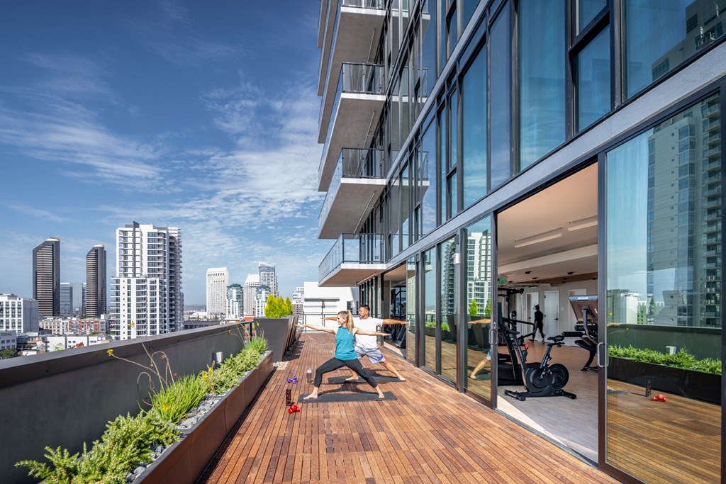a man and a woman doing yoga on a balcony with a cityscape in the