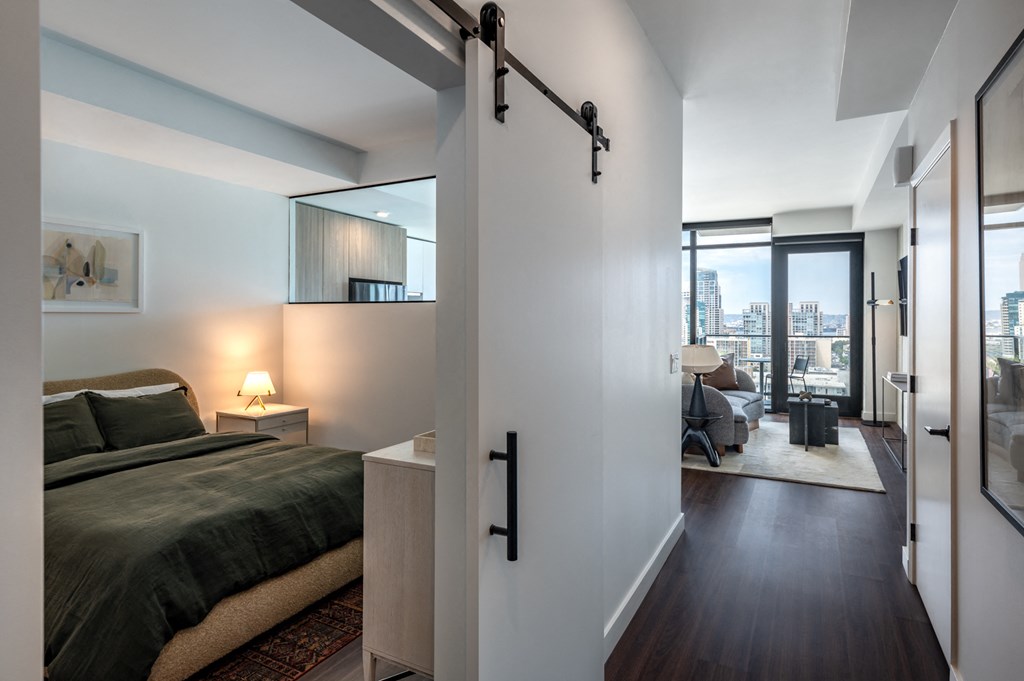 a bedroom with a bed and a sliding door to a living room