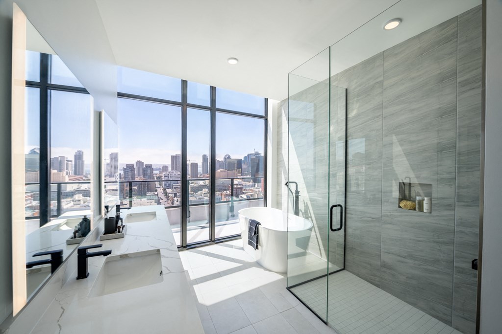 a bathroom with a shower and a tub and a view of the city