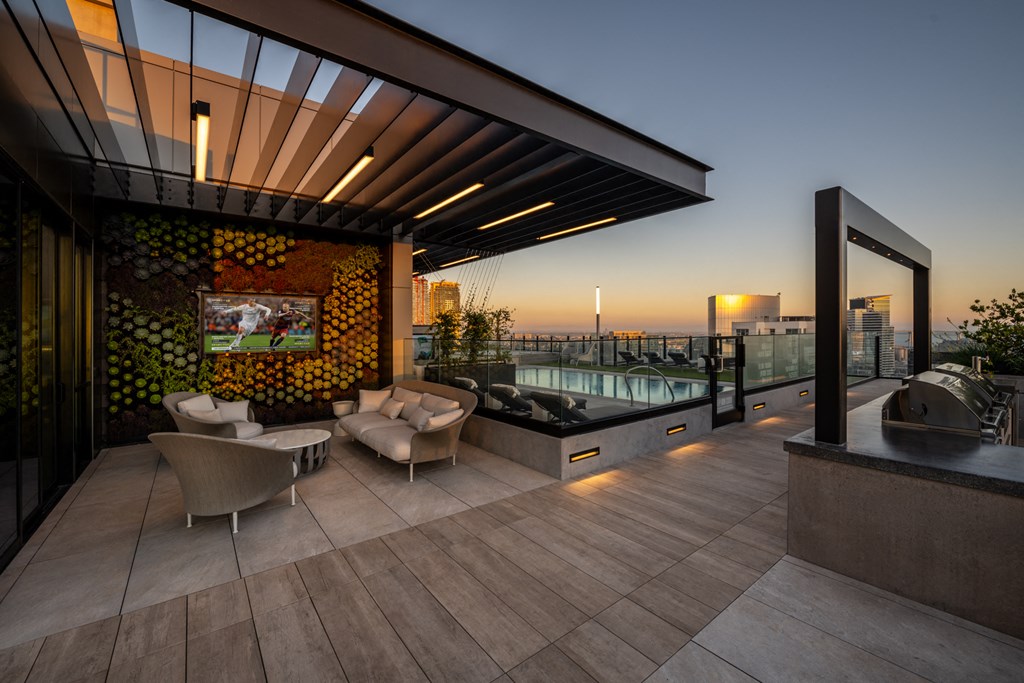 a rooftop terrace with a pool and chairs and a television