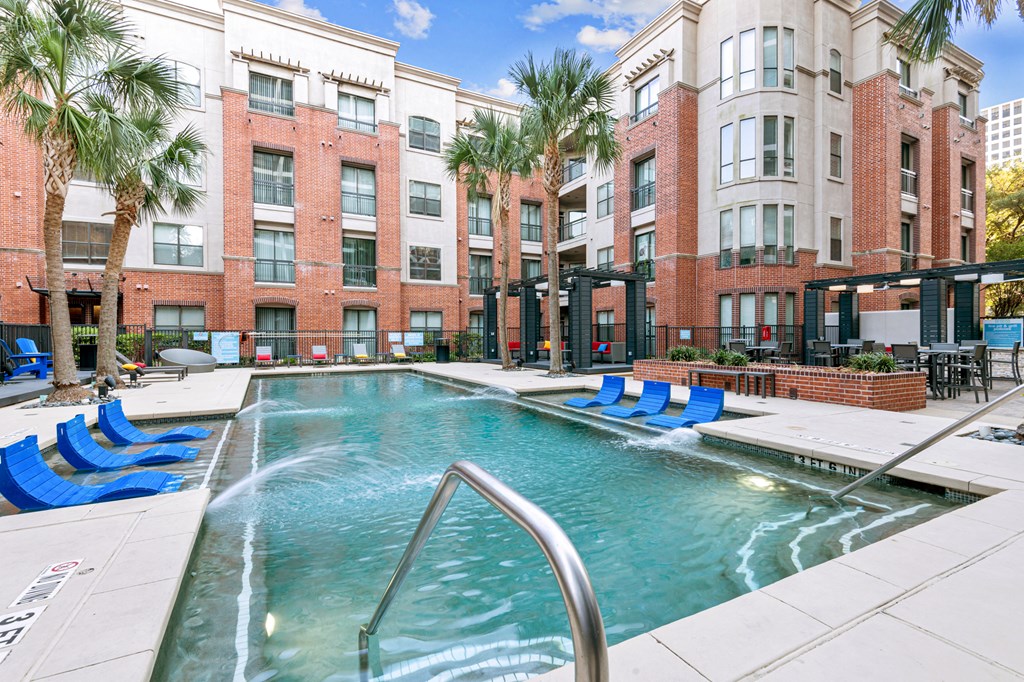 a swimming pool with blue lounge chairs in front of a building