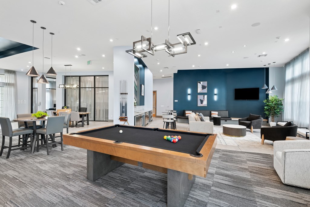 A pool table is in the middle of a room with a grey carpet.