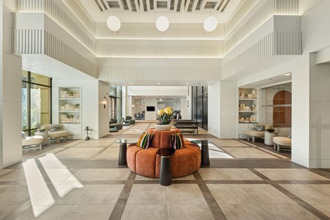 A spacious living room with a central orange sofa and a variety of seating options.