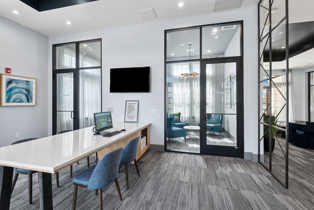 A conference room with a long table, chairs, and a television on the wall.