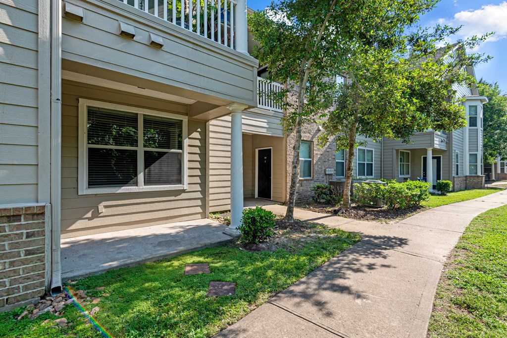 a sidewalk in front of an apartment building with trees