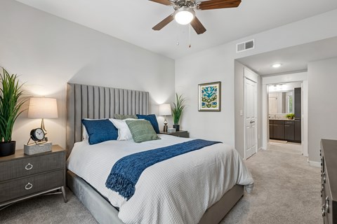 A bedroom with a bed, nightstand, and a ceiling fan.