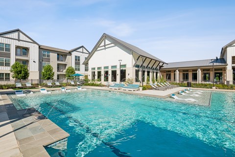 A large swimming pool in front of a building with a white roof.