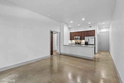 A spacious kitchen with white walls and a concrete floor.