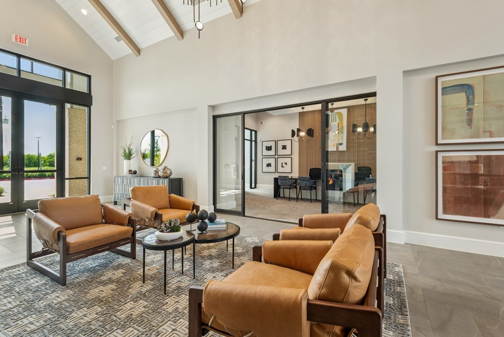 A living room with brown leather chairs and a glass table.