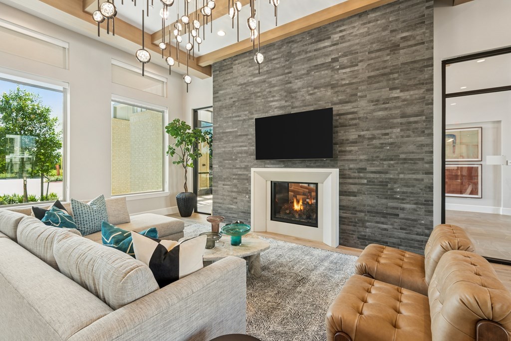 A modern living room with a stone fireplace and a flat screen TV mounted above it.
