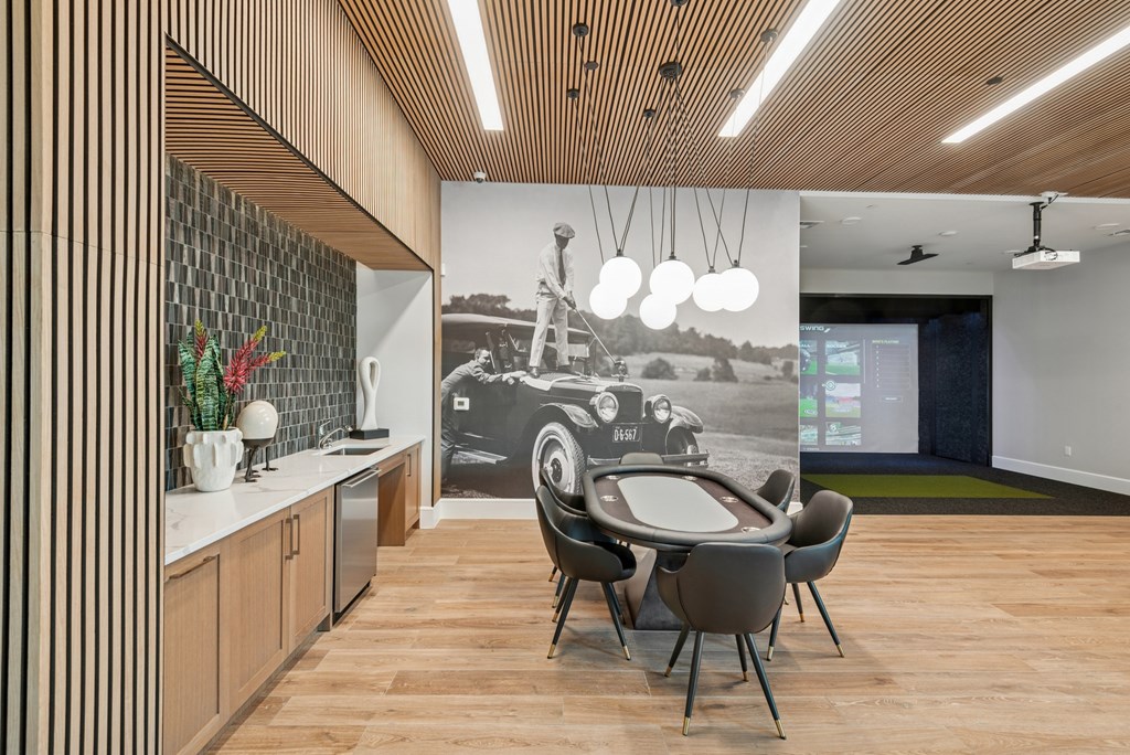 A conference room with a long table and chairs, a vintage car poster on the wall, and a green carpet on the floor.