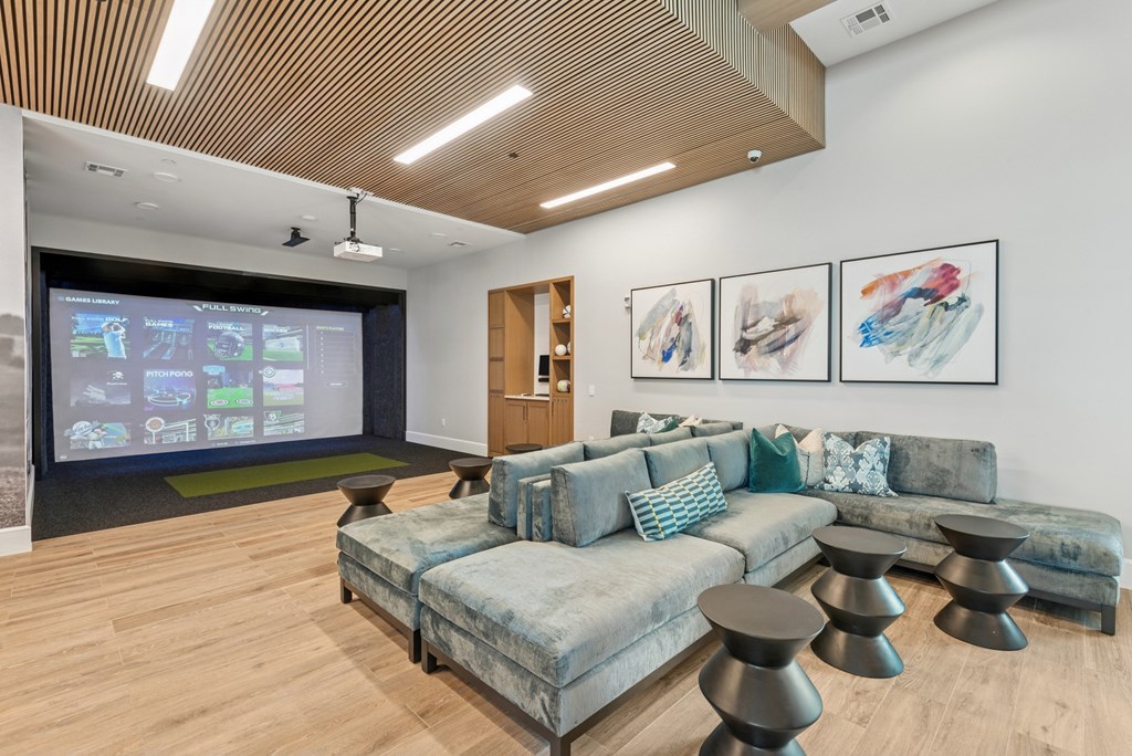 A modern living room with a large screen and comfortable seating.