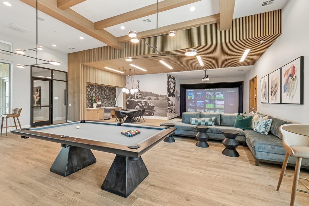 A pool table is in the middle of a room with a couch and a TV.