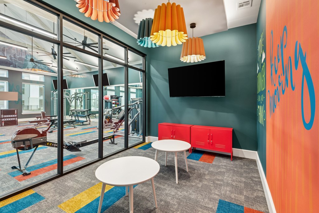 A room with a red bench and a black TV mounted on the wall.