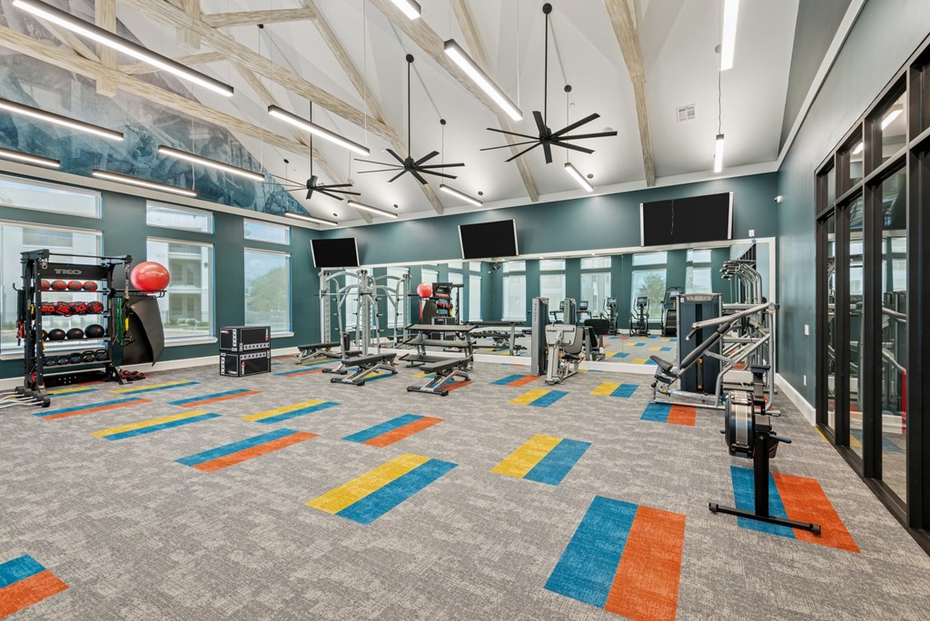 A gym with a grey carpet and a variety of exercise equipment.