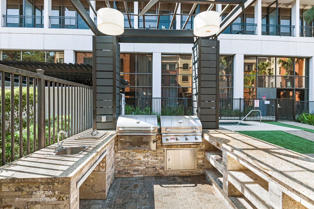 a patio with a grill and two sinks in front of a building