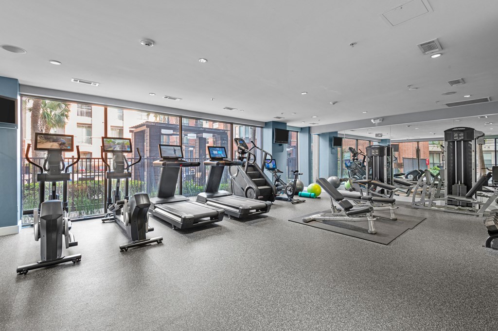 a gym with treadmills and other exercise equipment in a building with large windows