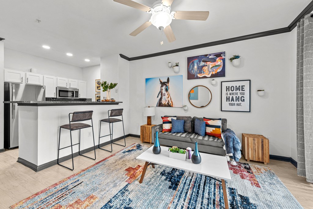 A modern kitchen with a bar area and a living room area with a couch and a rug.