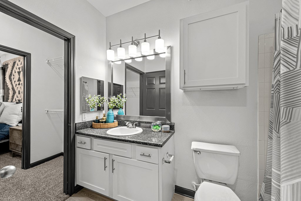 A bathroom with a white toilet, a sink with a mirror above it, and a shower area.