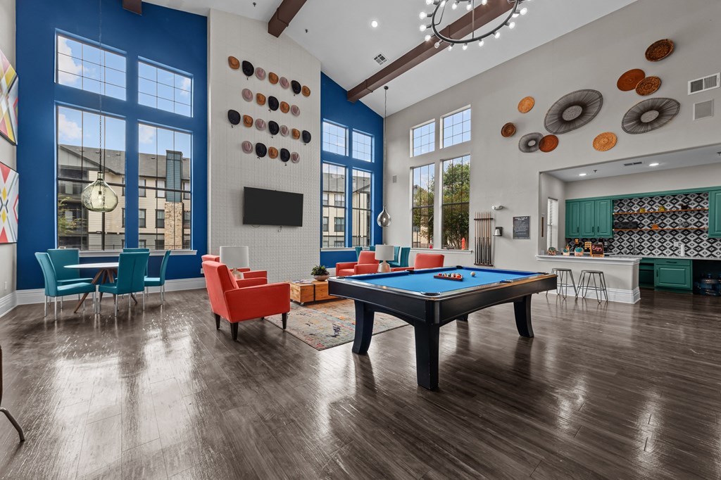 A pool table is in the middle of a room with a blue wall and a television.