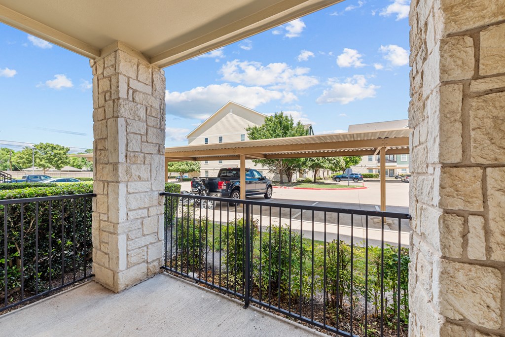 the view of a parking lot from a balcony with a metal gate