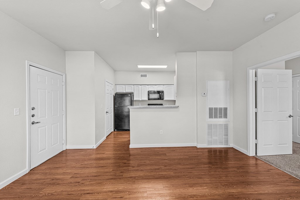 a renovated living room and kitchen with white walls and wood floors