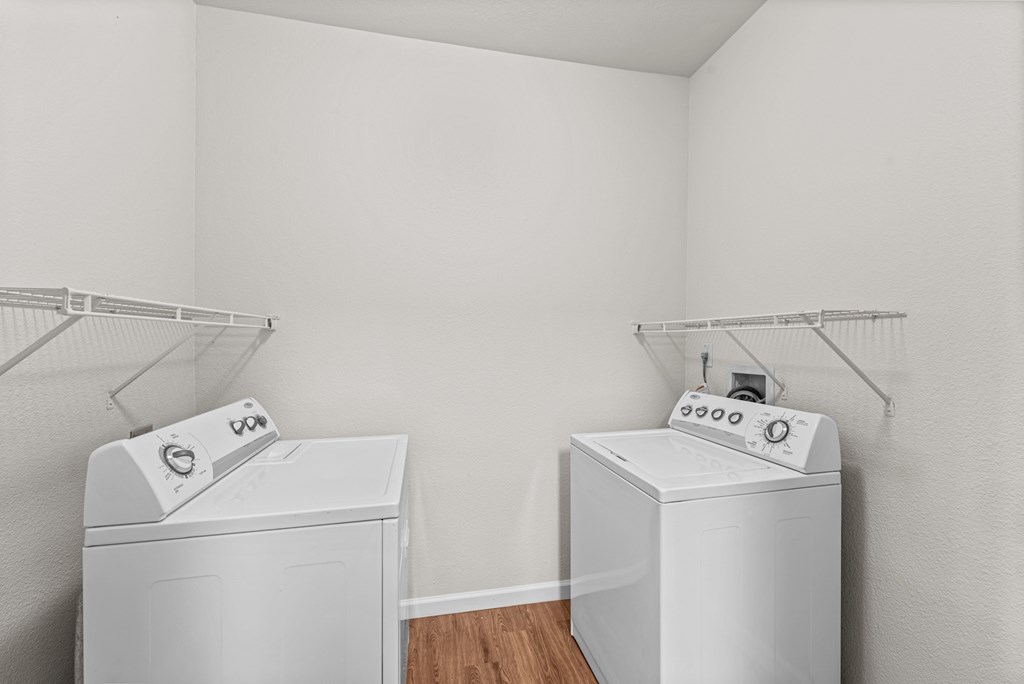 two white washers and dryers in a room with white walls and wood floor