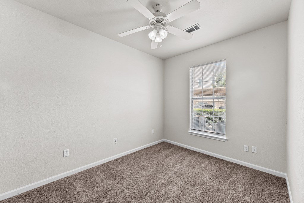 an empty room with carpet and a ceiling fan
