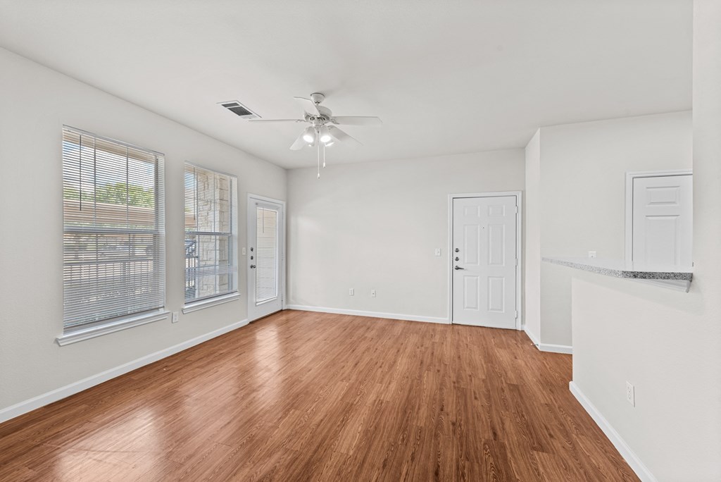an empty living room with wood flooring and a ceiling fan
