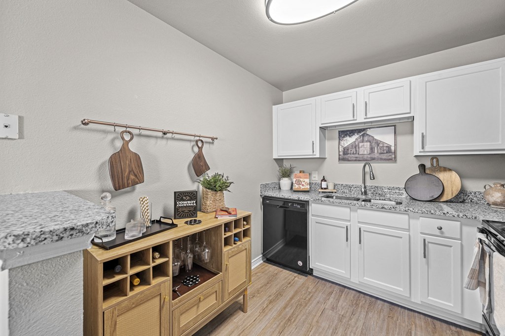 a kitchen with white cabinets and granite counter tops and a black oven and a sink