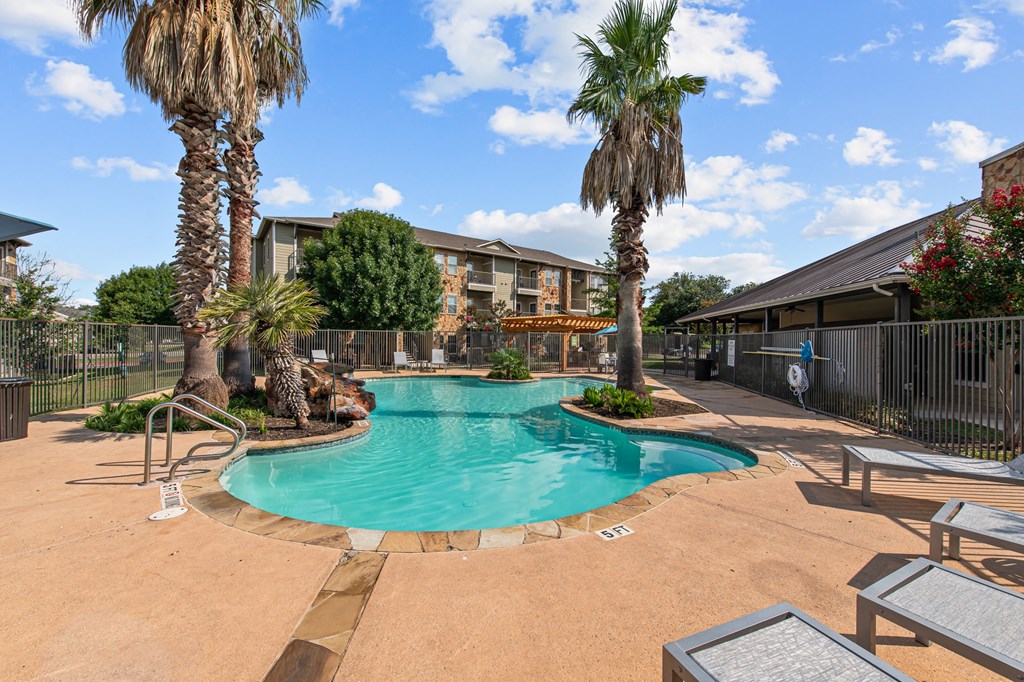 a swimming pool with palm trees and a building in the background
