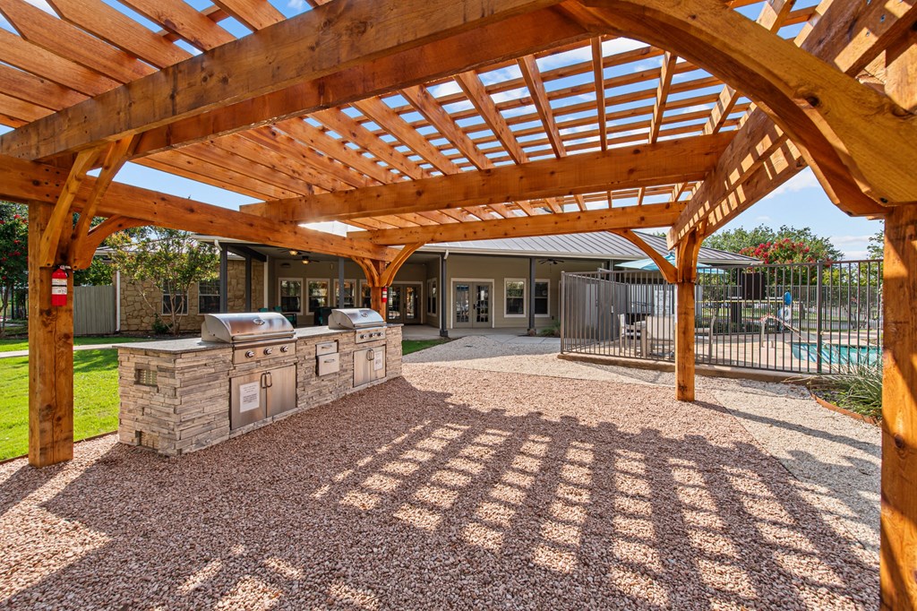 a patio with a stone grill and a wooden roof