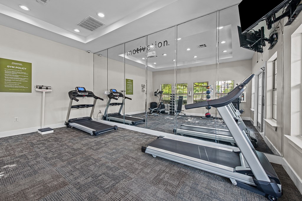 a gym with treadmills and other exercise equipment in a glass walled room