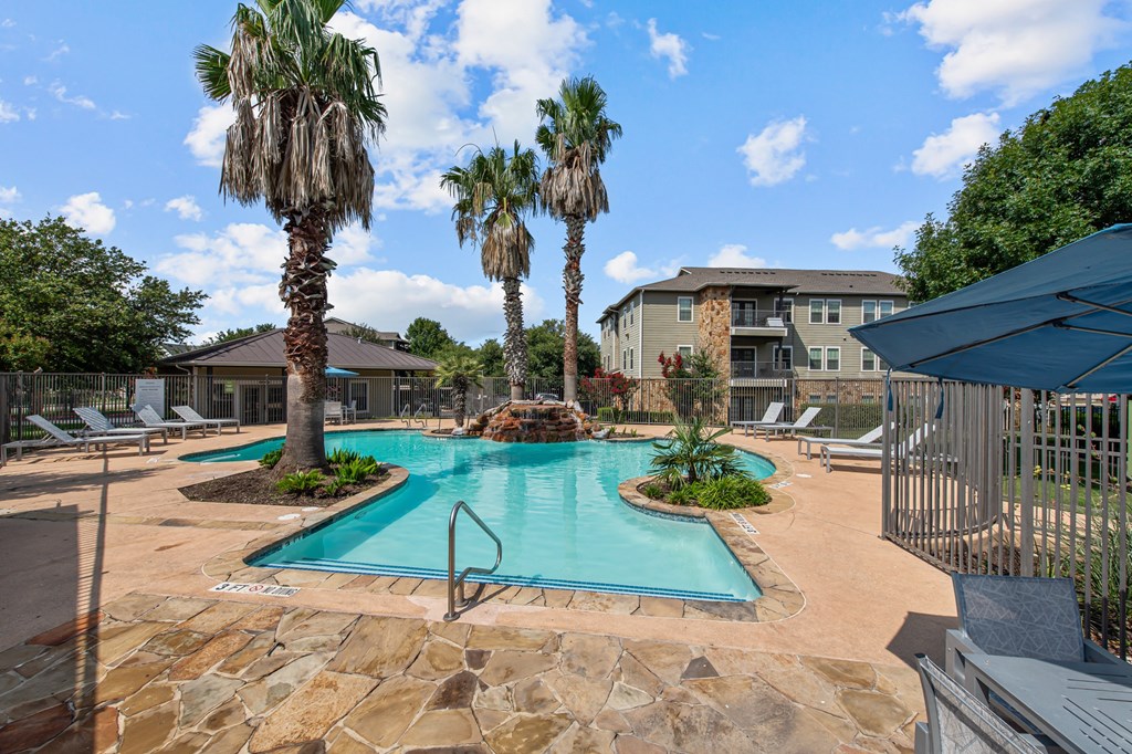 a swimming pool with palm trees and a building in the background