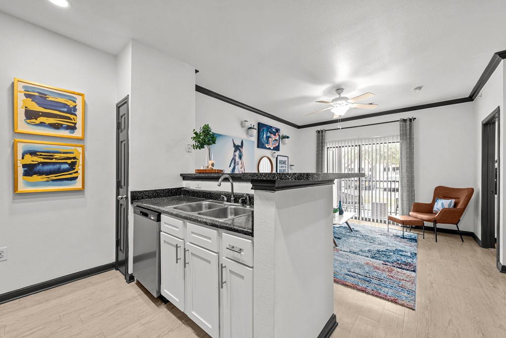 A kitchen with white cabinets and a black countertop.