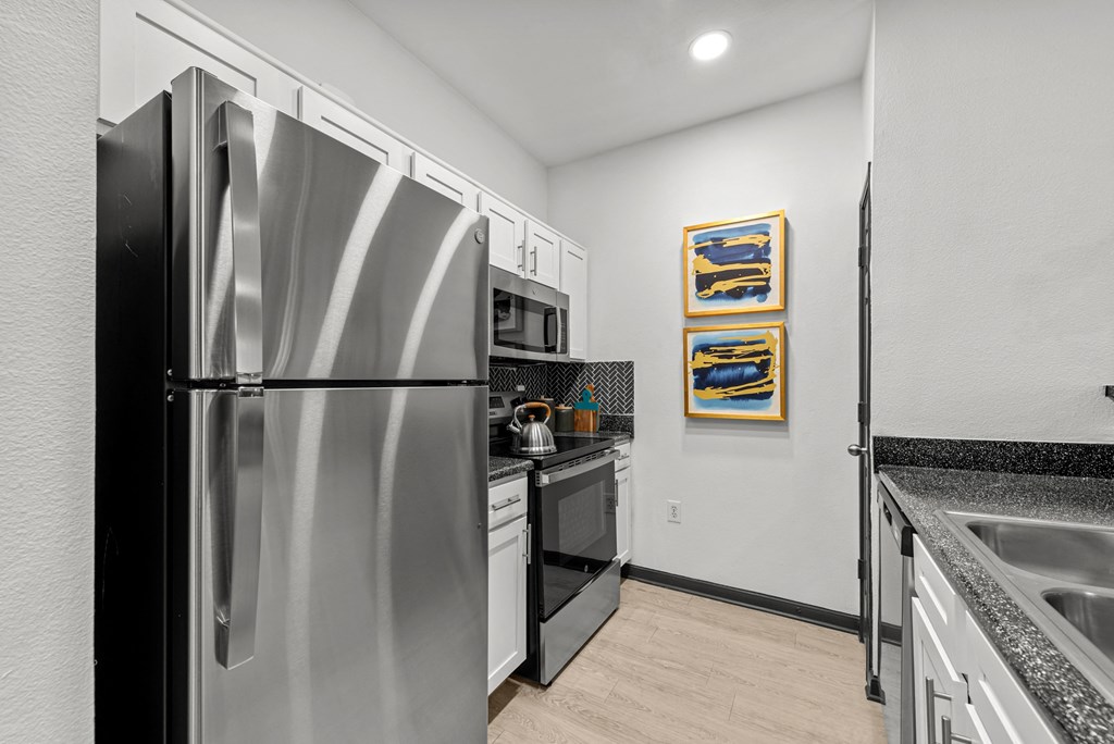 A kitchen with a stainless steel refrigerator and a painting on the wall.